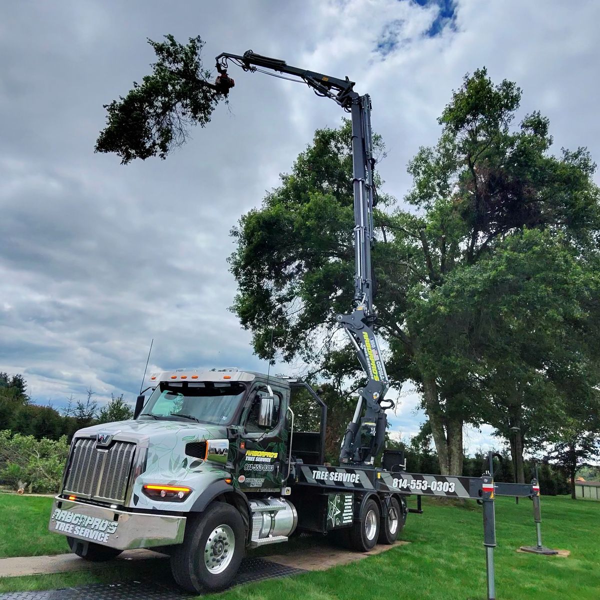 Arbor Pro’s crane truck lifting a branch on a lawn job