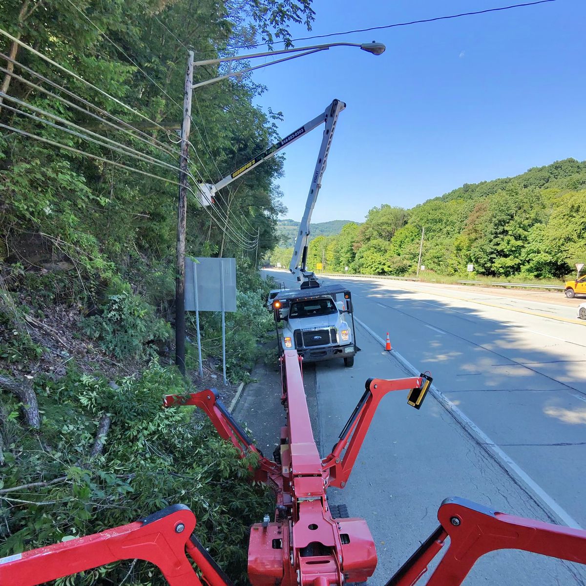 Spider lift and bucket truck working on a roadside utility line